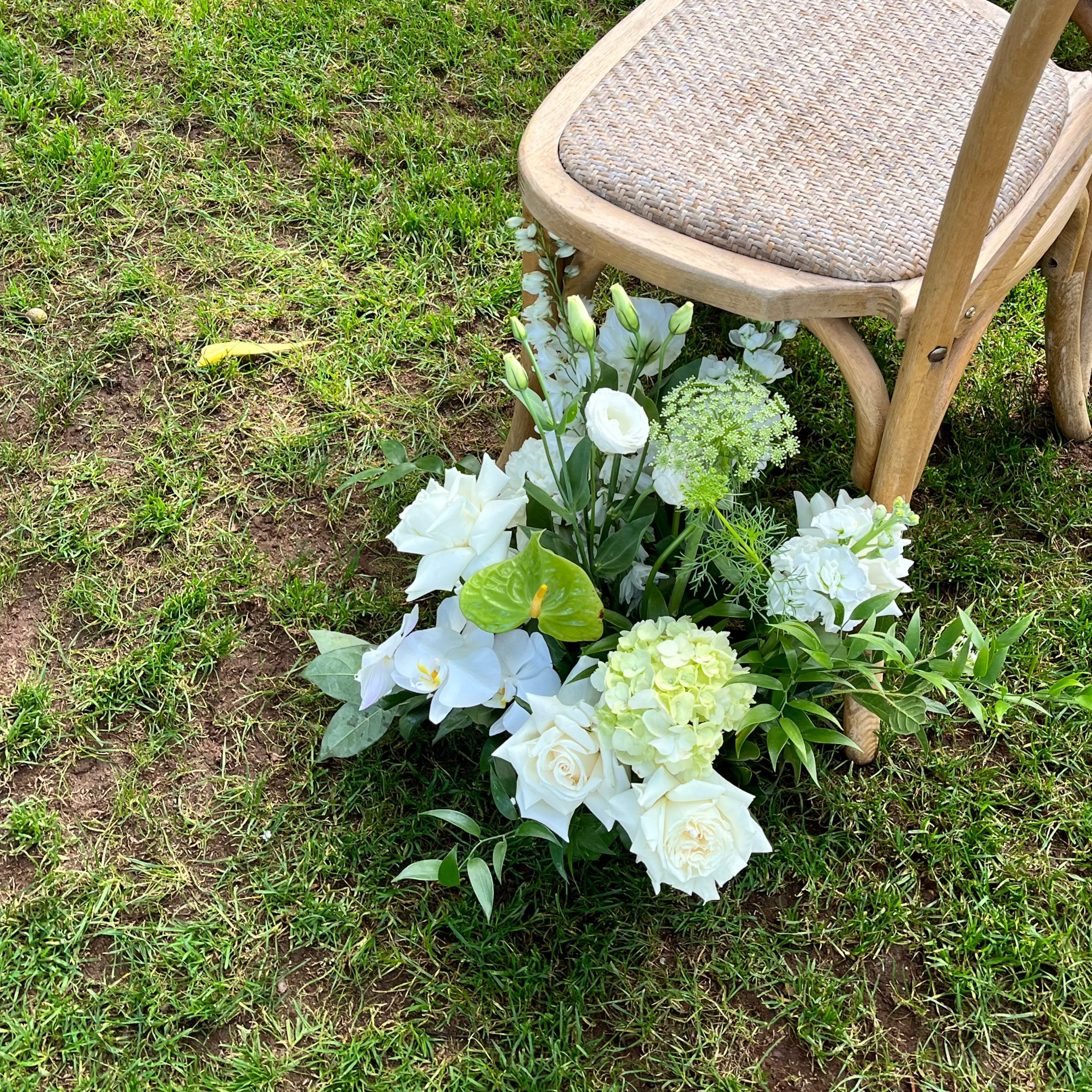 green and white wedding floral arrangement on grass next to a chair at Gabbinbar