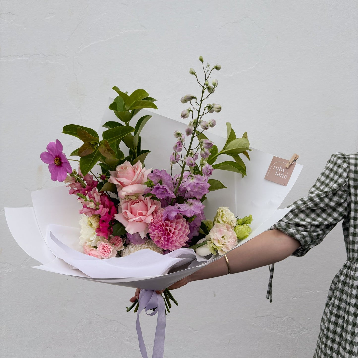 Bouquet of flowers held by a person against a plain background