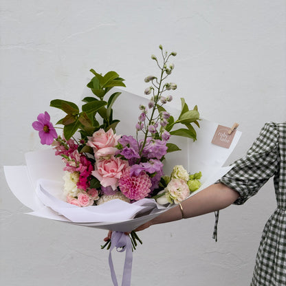 Bouquet of flowers held by a person against a plain background