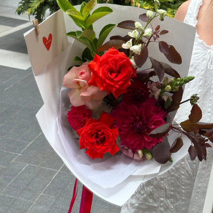 Bouquet of flowers with a card held by a person in a white dress